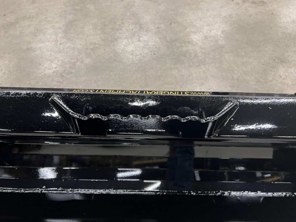Close-up of Stinger Series 2 skid steer bucket showing welded serrated step for easier machine cab access