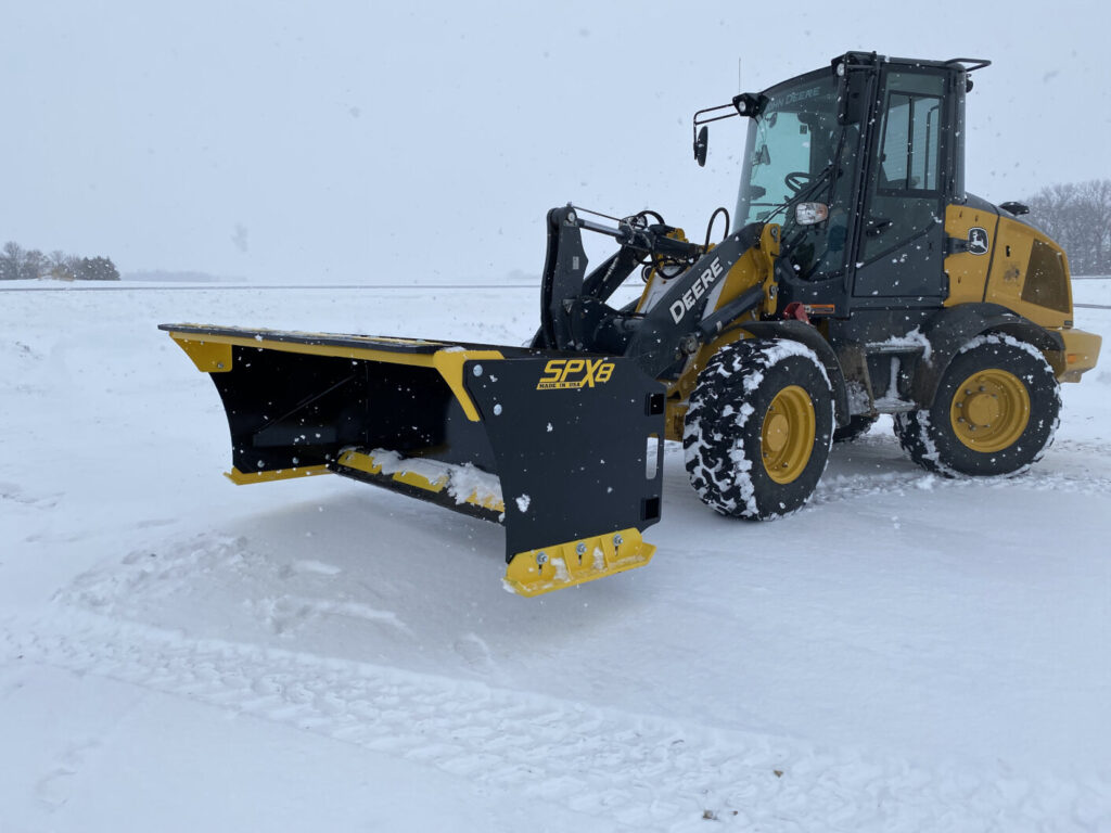 Stinger SPX8 snow pusher mounted on a John Deere wheel loader during heavy snowfall