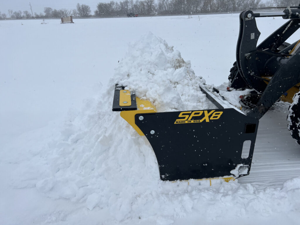 Stinger SPX8 snow pusher pushing a large snow pile with wide box containment