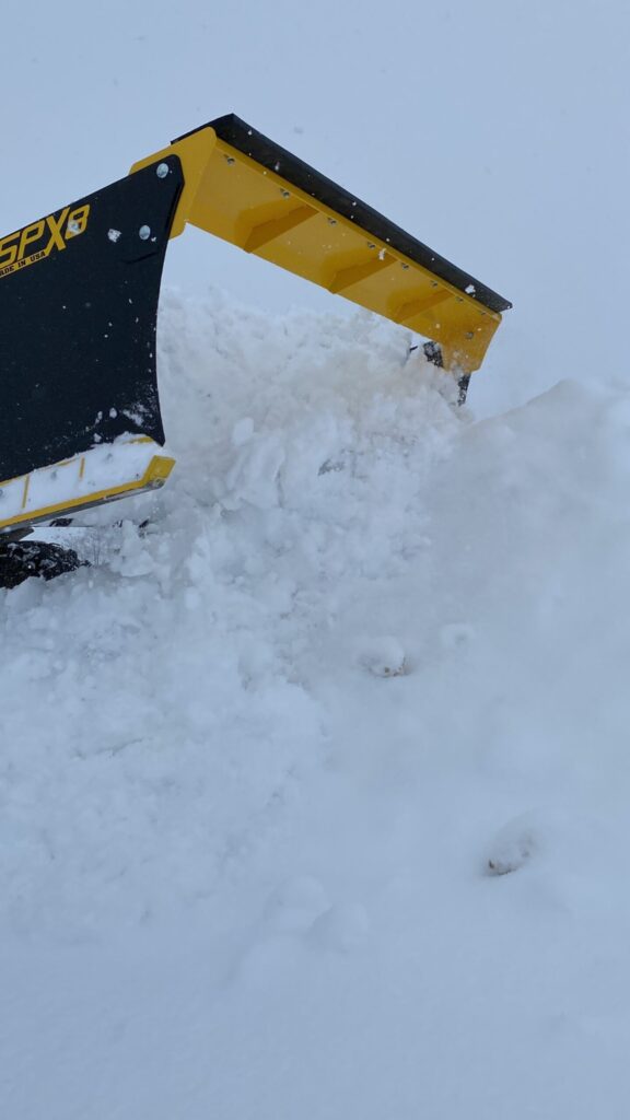 Stinger SPX8 snow pusher stacking a large pile of snow with a wheel loader