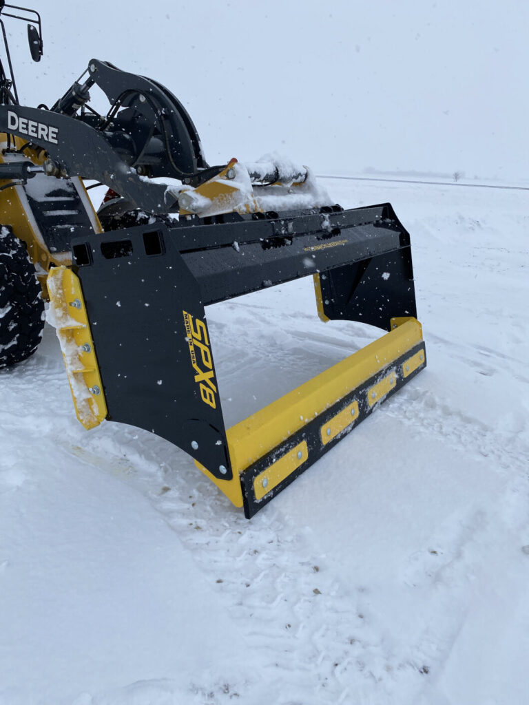Stinger SPX8 snow pusher showing dragback and mounted on a John Deere wheel loader
