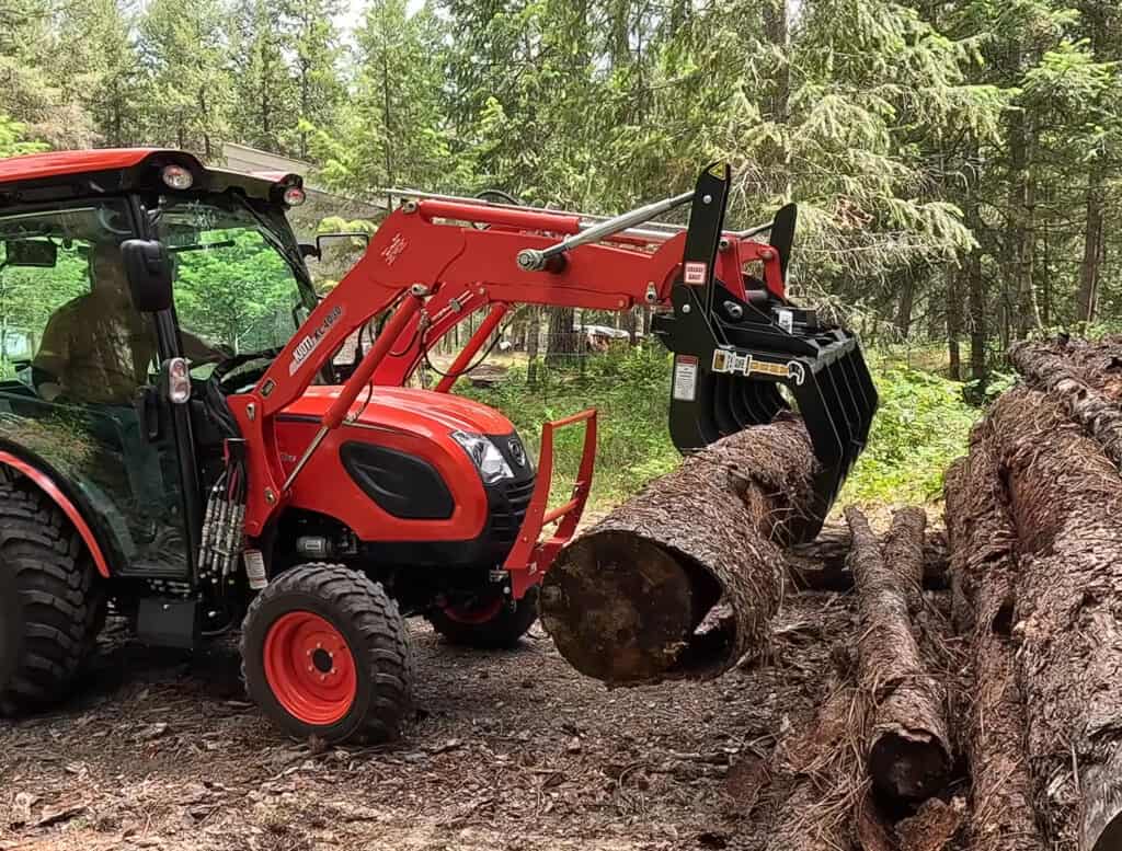 ANBO CLASP-IT mechanical grapple on a Kioti compact tractor grabbing a large log from a timber pile