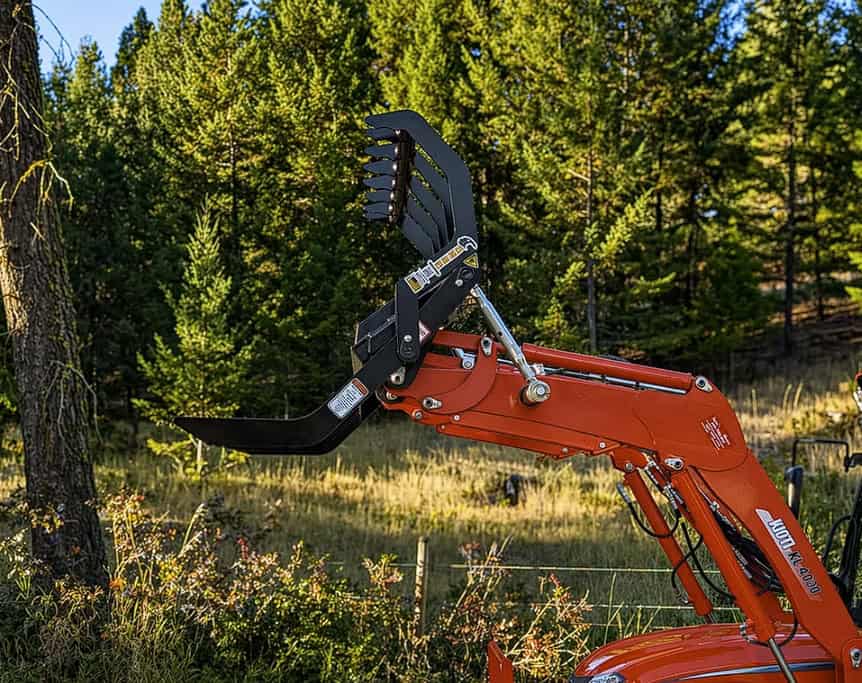 Side view of an open ANBO CLASP-IT mechanical grapple mounted on the loader of a Kioti compact tractor