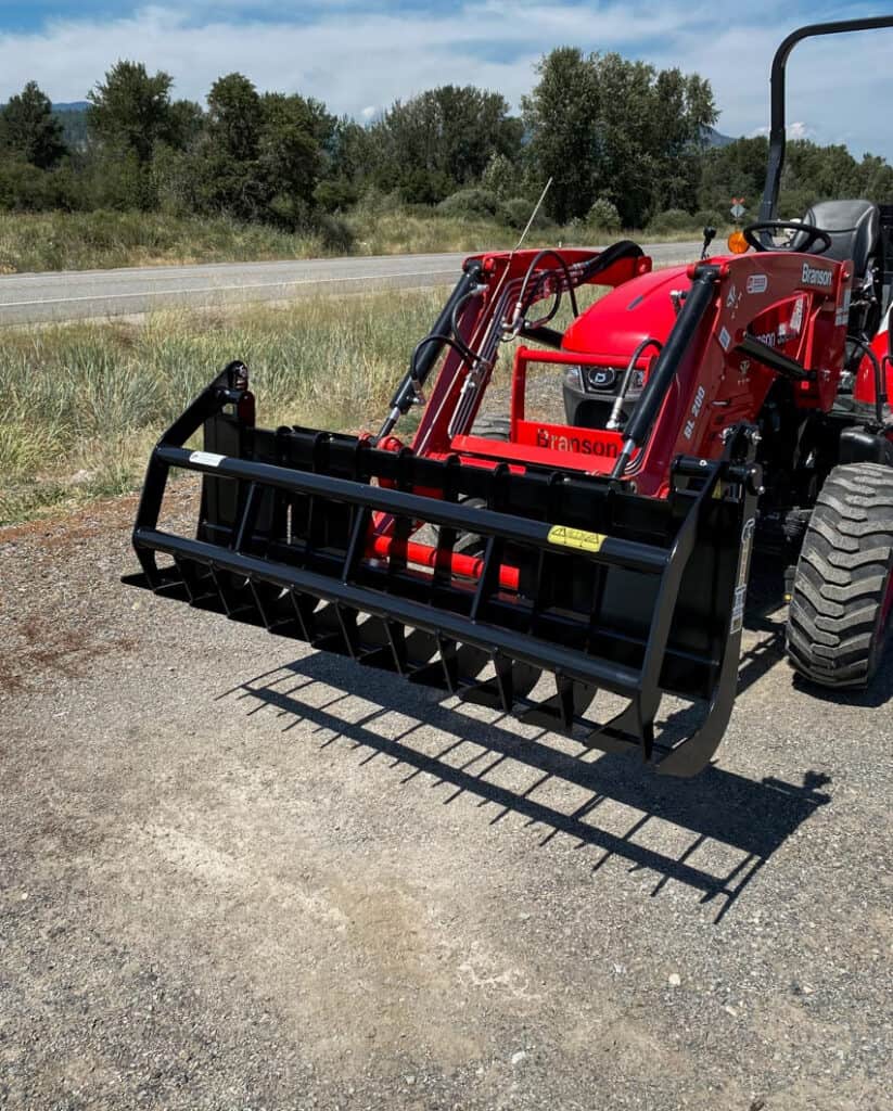 Front view of the ANBO GR45 grapple rake mounted on a Branson compact tractor with the grapple closed