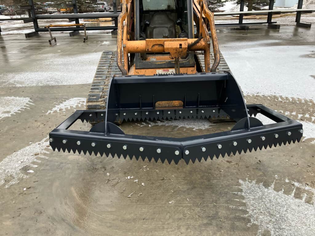 Front view of the ECHO 86 inch skid steer ice scraper and scarifier mounted on a CASE compact track loader