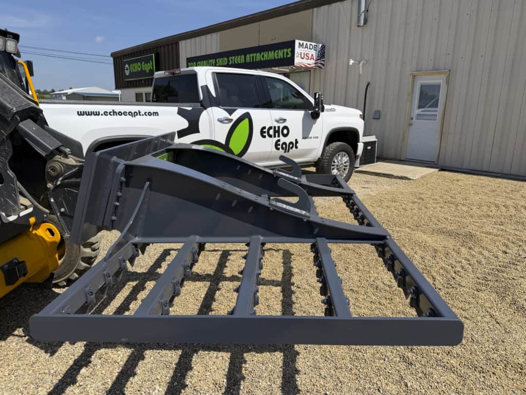 ECHO 92 inch skid steer drag landscape rake mounted on a JCB loader and shown from the side angle