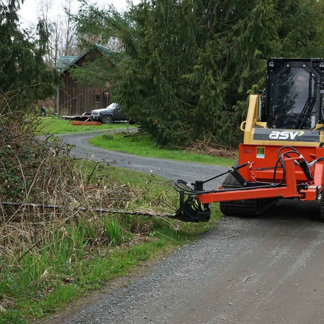 Eterra skid steer sickle bar mower on an ASV compact track loader cutting brush along a driveway