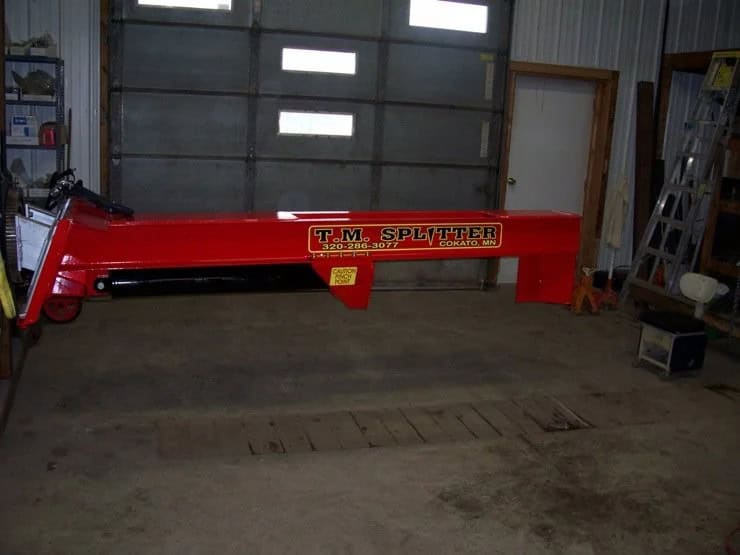 Side view of TM Manufacturing Pro 1 skid steer log splitter showing hydraulic cylinder and fixed wedge