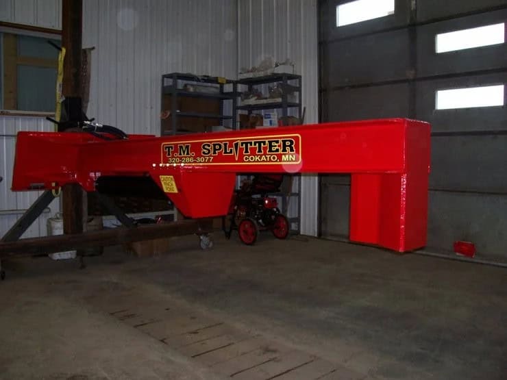 TM Manufacturing Pro 1 skid steer log splitter shown indoors from the side with fixed wedge