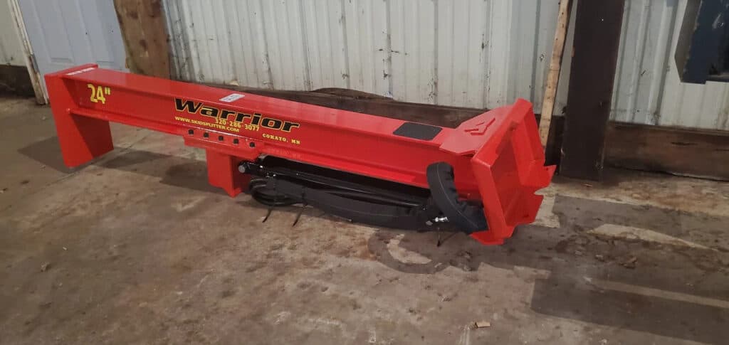 TM Manufacturing Warrior 24 inch skid steer log splitter shown indoors with hydraulic cylinder, hoses and mounting plate