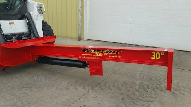 TM Manufacturing Warrior 30 inch skid steer log splitter attached to a skid steer and shown from the side