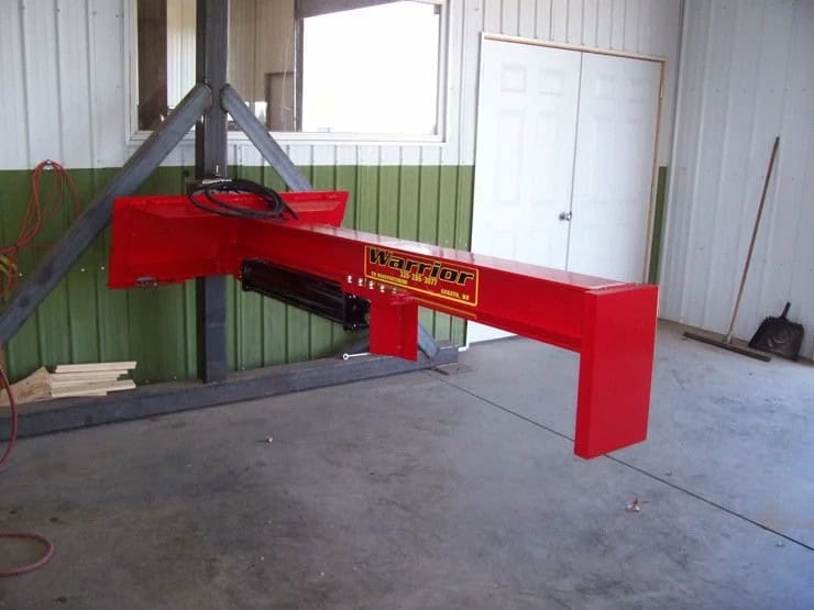 TM Manufacturing Warrior skid steer log splitter shown indoors from the side with hydraulic cylinder and beam