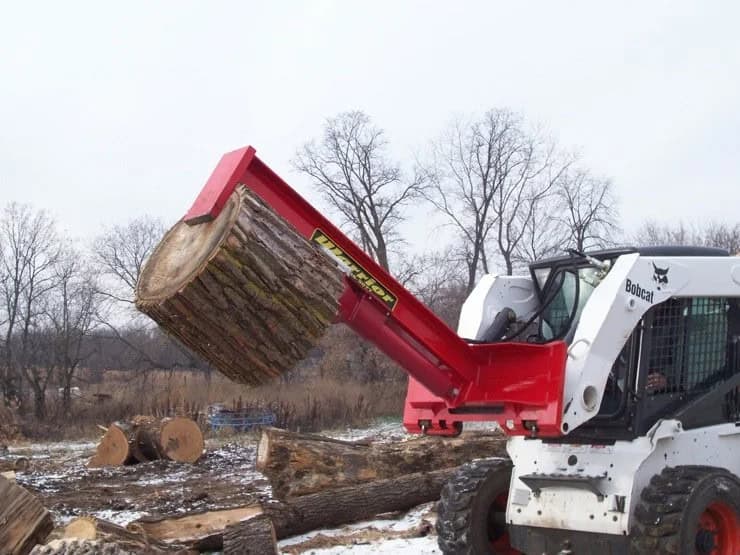 Bobcat skid steer using a TM Manufacturing Warrior log splitter to lift and reposition a large log round