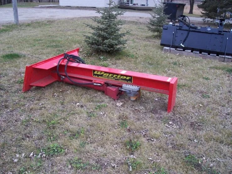 TM Manufacturing Warrior skid steer log splitter outdoors showing the beam, hydraulic hoses and splitting assembly