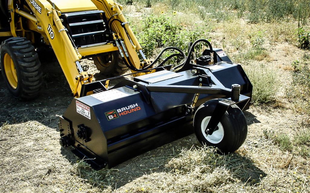 Close view of the BrushHound 72F Skid Steer Flail Mower showing the front caster wheel, mower housing, and hydraulic connections.