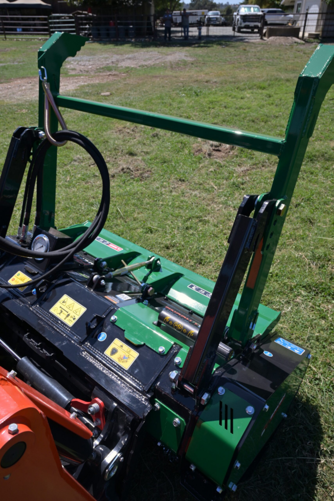 Close view of the BrushHound FHX66 Defender hydraulic system, pressure gauge, hoses, and adjustable tree bumper.