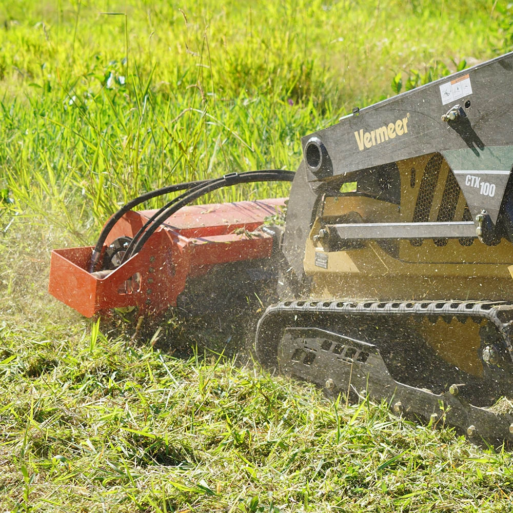 Eterra Sidewinder flail mower clearing heavy grass with a Vermeer mini skid steer