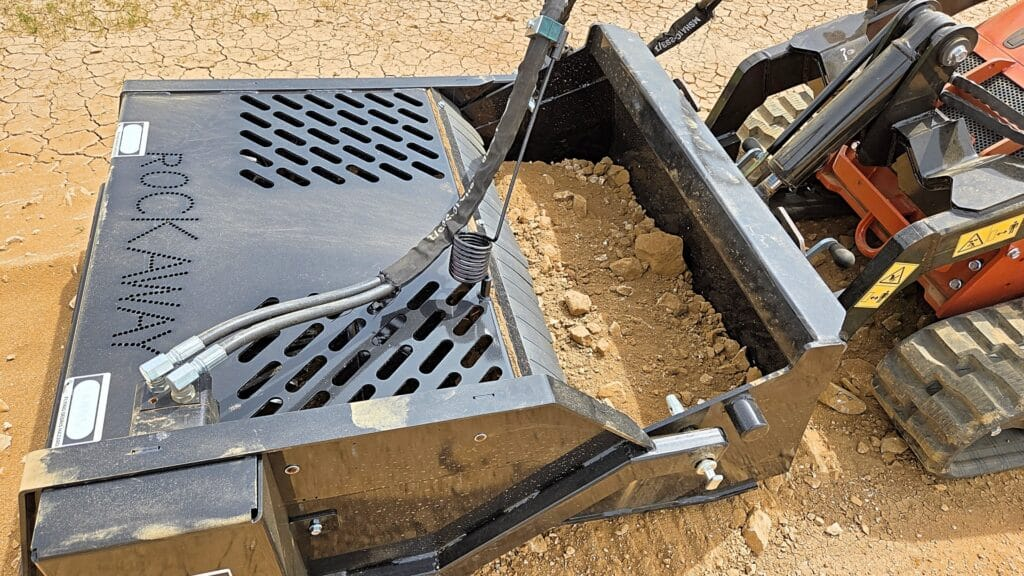 Ideal Rockaway 4415 mini skid steer landscape rake collecting rocks in its bucket