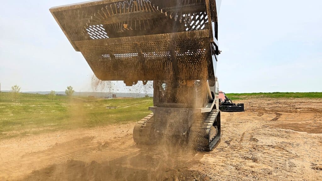 Ideal Rockaway 8415 skid steer rock rake dumping collected rocks, soil, and debris
