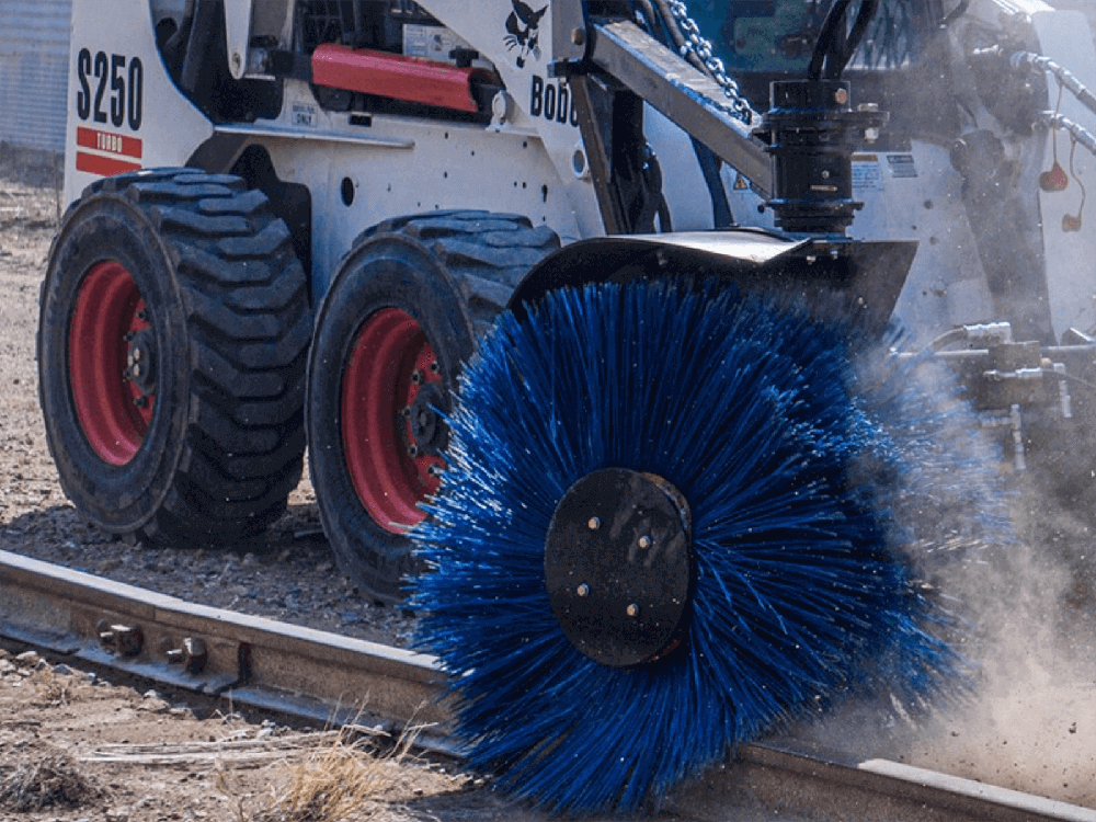 Maxx Attachments Feed Bunk Sweeper cleaning debris alongside railroad tracks