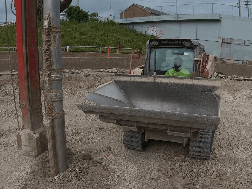 Front view of a Maxx Attachments Side Dump Bucket mounted on a skid steer
