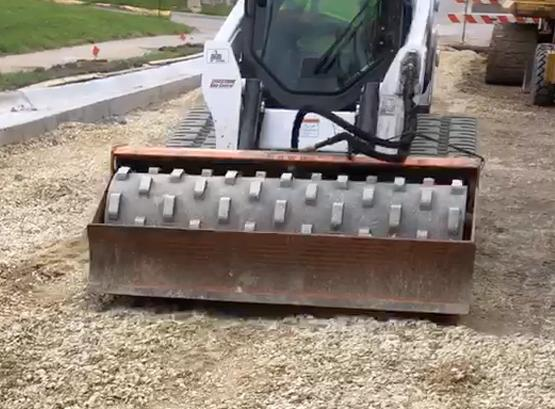 MBW padded drum skid steer vibratory roller compacting gravel on a job site