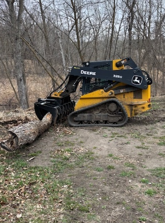John Deere compact track loader gripping a fallen log with a Prime Attachments HD Dual Clam Grapple skid steer attachment