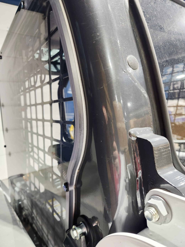Close-up of a SHIELDS Bobcat M Series polycarbonate side window installed in the cab frame