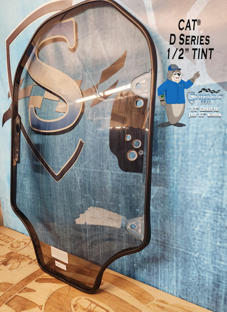 Angled view of the SHIELDS CAT D Series half-inch tinted polycarbonate skid steer windshield with SHIELDS Seal