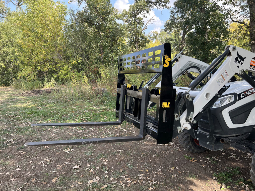 Stinger CPF compact pallet forks front left view mounted on Bobcat compact tractor with see-through guard