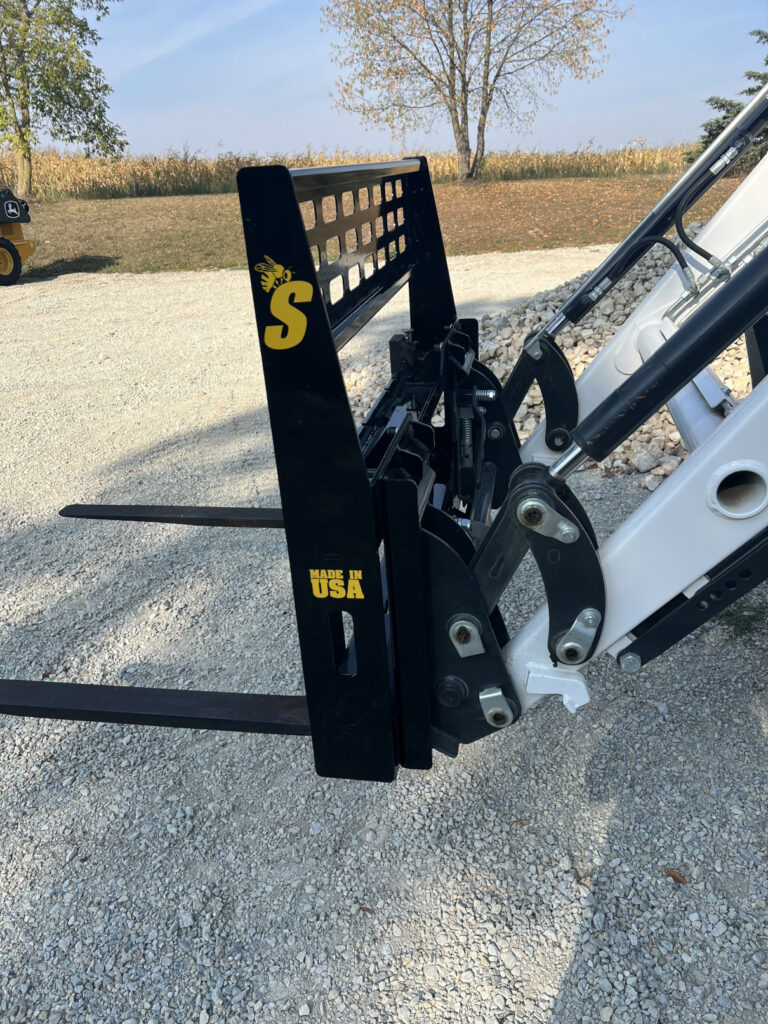 Stinger CPF compact pallet forks side view mounted on compact tractor showing frame, forks and loader linkage