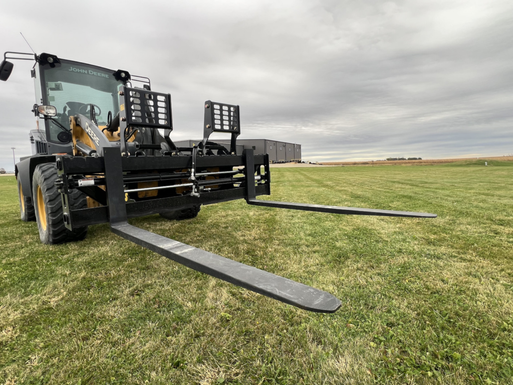 Front-right view of Stinger PF3H hydraulic pallet forks mounted on a John Deere wheel loader