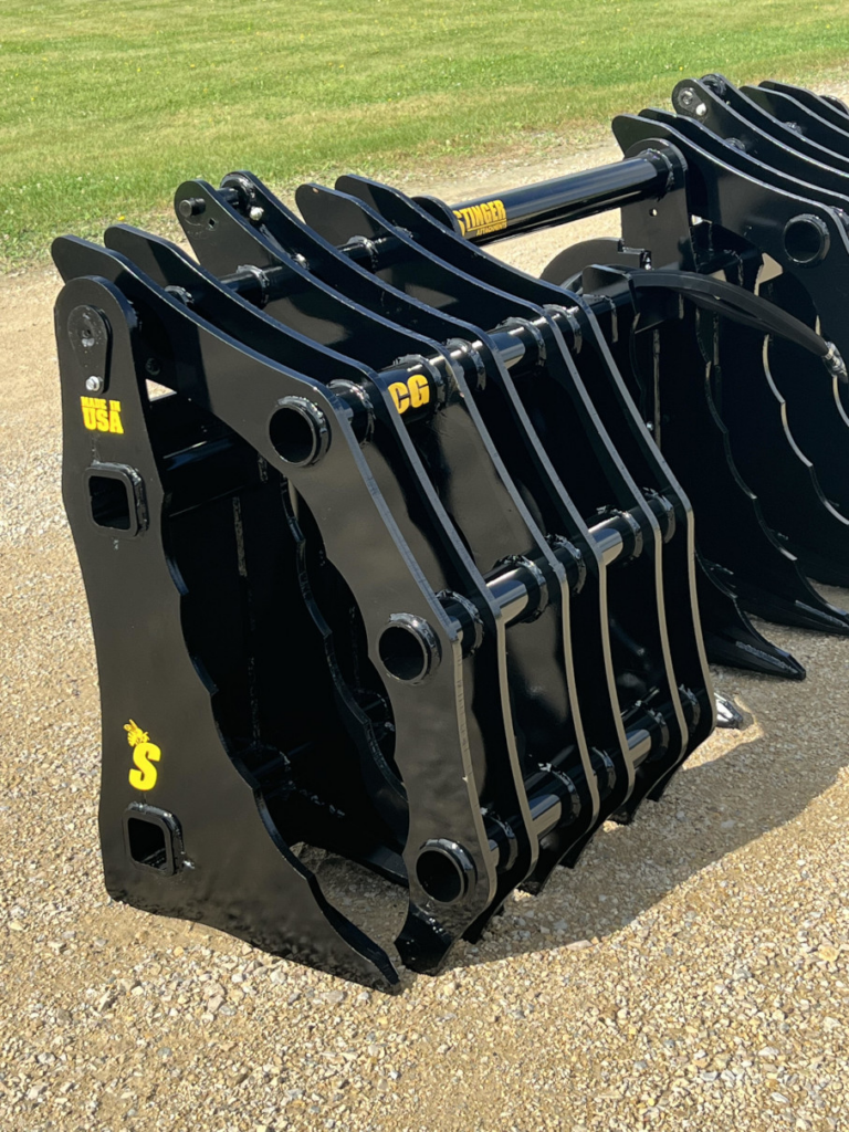 Close-up angled view of the Stinger Severe Duty Wheel Loader Clam Grapple showing layered grapple arms, pivot shafts, and steel tine construction