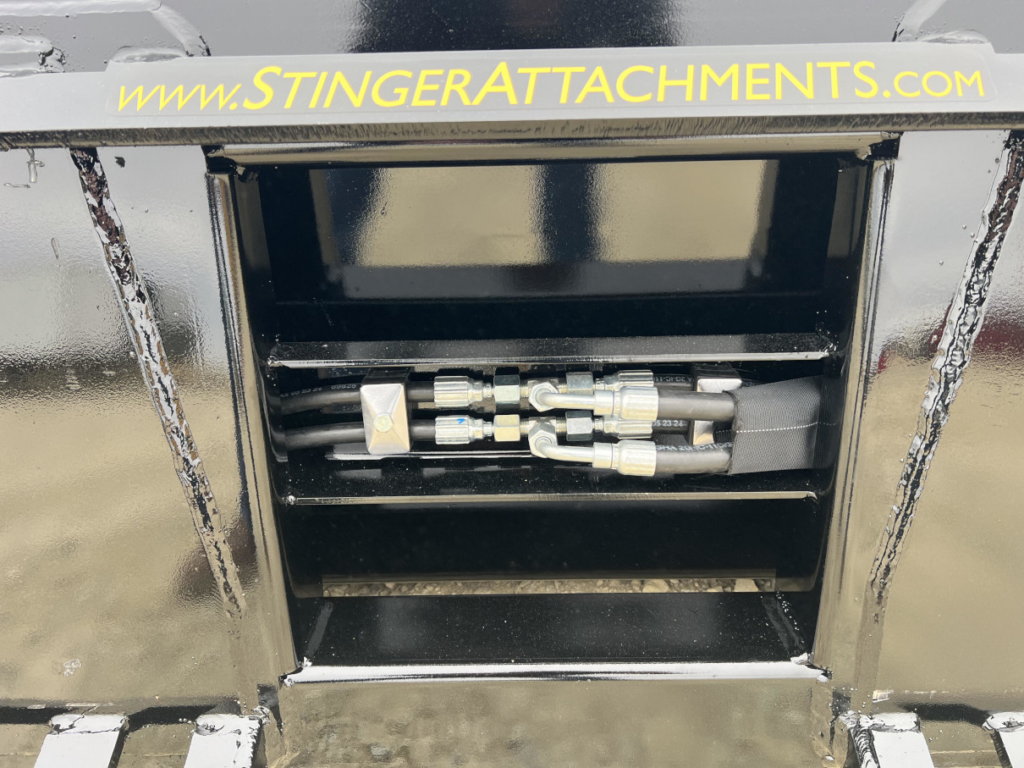 Close-up of the hydraulic hose routing and protected hydraulic connections on the Stinger skid steer hydraulic dump bucket