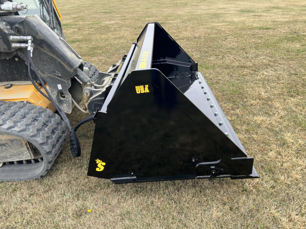 Side view of the Stinger skid steer hydraulic dump bucket mounted on a compact track loader