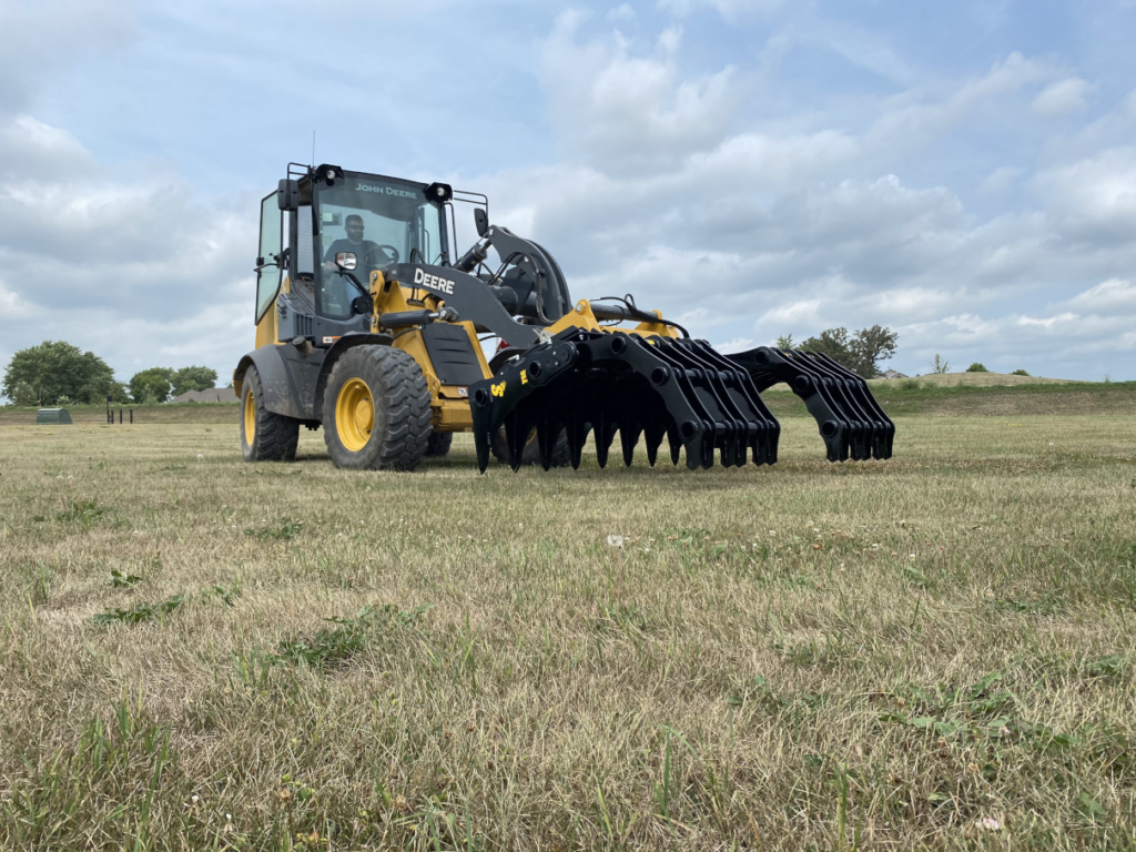 Low angled view of the Stinger Wheel Loader Clam Grapple opened near ground level on a John Deere wheel loader