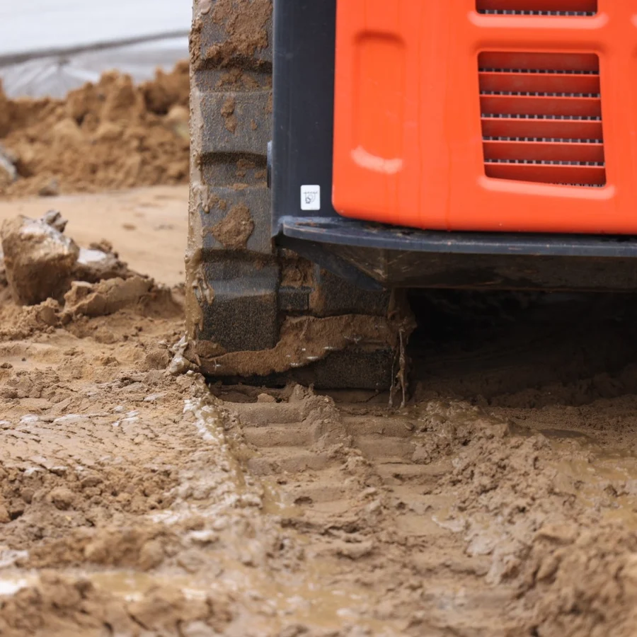 Rubber track equipped with Stout TrackClaws traction chains in muddy conditions