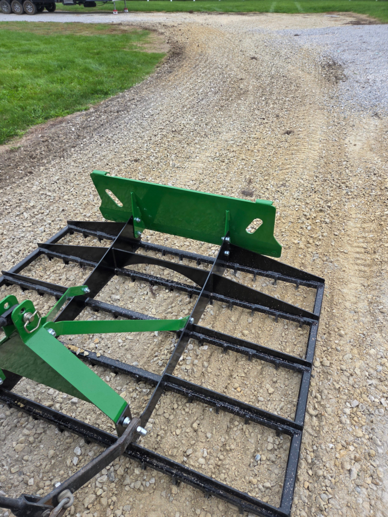 SWAT Metal Works 72" Compact Land Rake working across a gravel surface with a compact tractor.