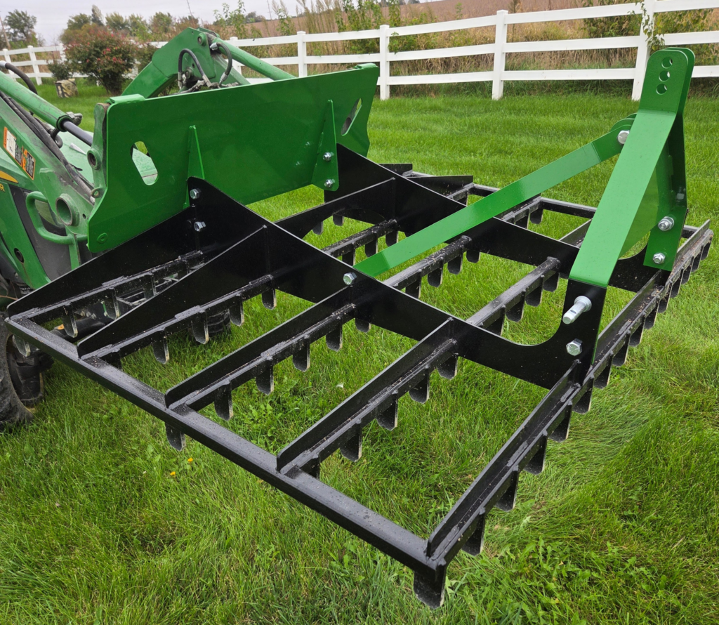 SWAT Metal Works 72" Compact Land Rake showing the steel grading frame, multiple tooth rows, and Universal Skid Steer Quick Attach mount.
