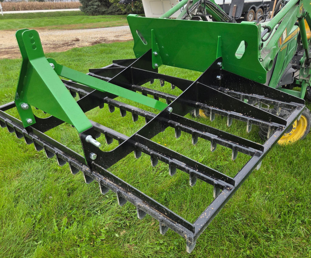 Rear angle of the SWAT Metal Works 72" Compact Land Rake configured for full-size skid steer use.