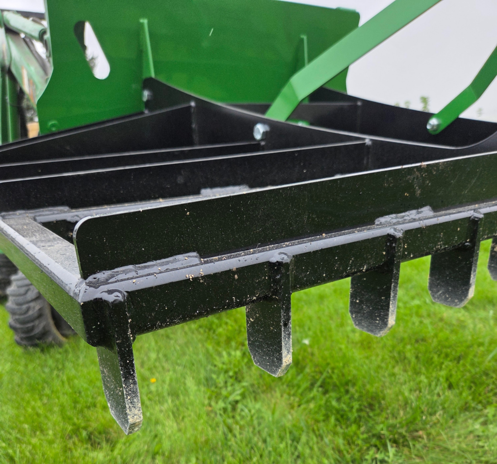 Close-up of the SWAT Metal Works 72" Compact Land Rake steel teeth and grading rails.