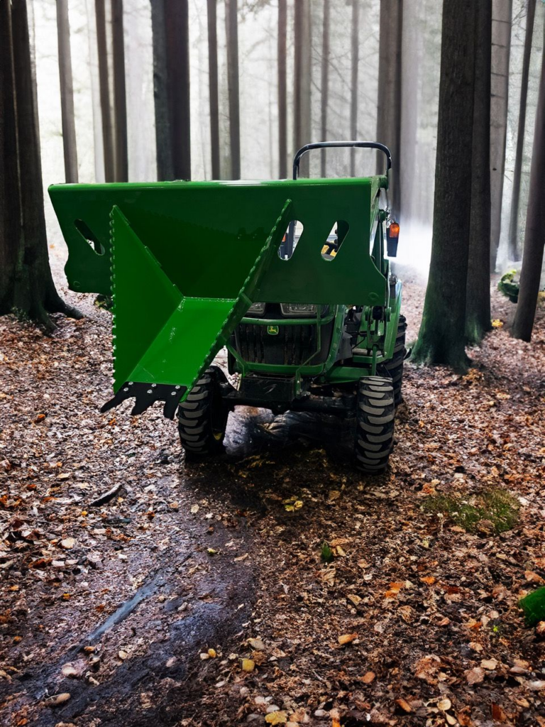 SWAT Metal Works Heavy Duty Stump Buster in John Deere Green mounted on a compact tractor in a wooded setting.