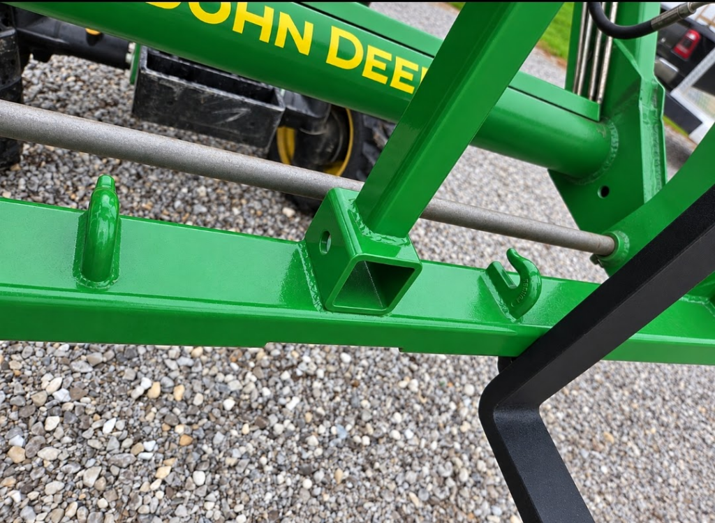 Close-up of the SWAT Metal Works Light Duty Pallet Forks in John Deere Green showing the center receiver and fork rail details.