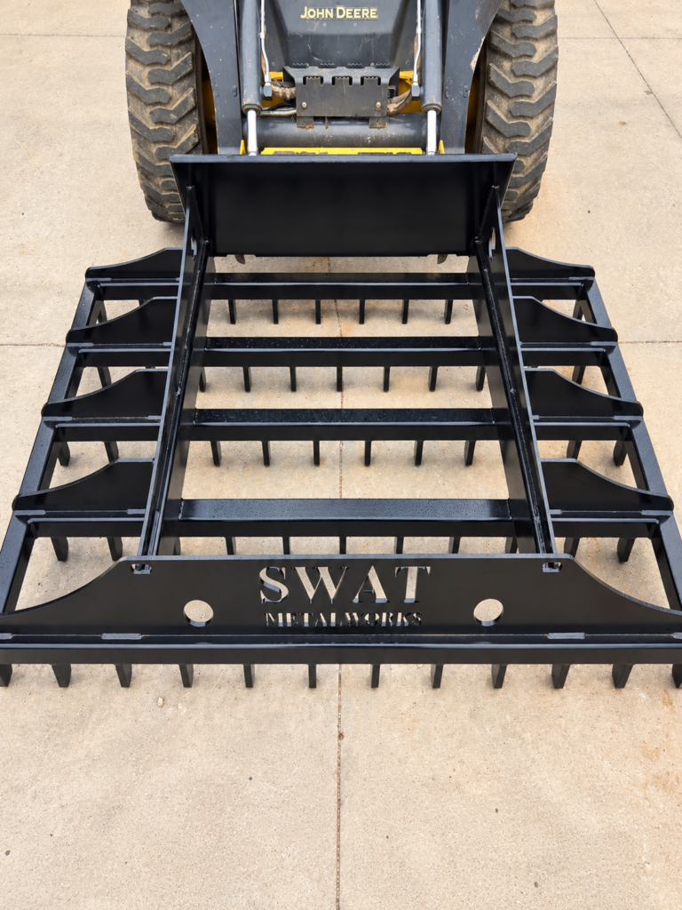 Front overhead view of the SWAT Metal Works Skid Steer Land Rake showing the full rake width and scarifier rows