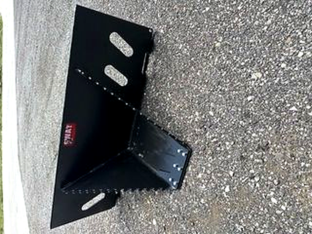 Angled view of the black SWAT Metal Works Mini Stump Buster showing the narrow digging snout, serrated sides, and quick-attach mounting plate.