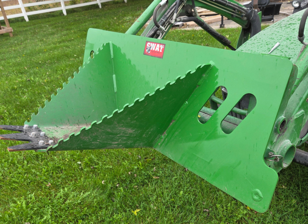 SWAT Metal Works Mini Stump Buster in John Deere Green mounted on a tractor, showing the serrated sides and replaceable AR400 cutting edge from the left side.